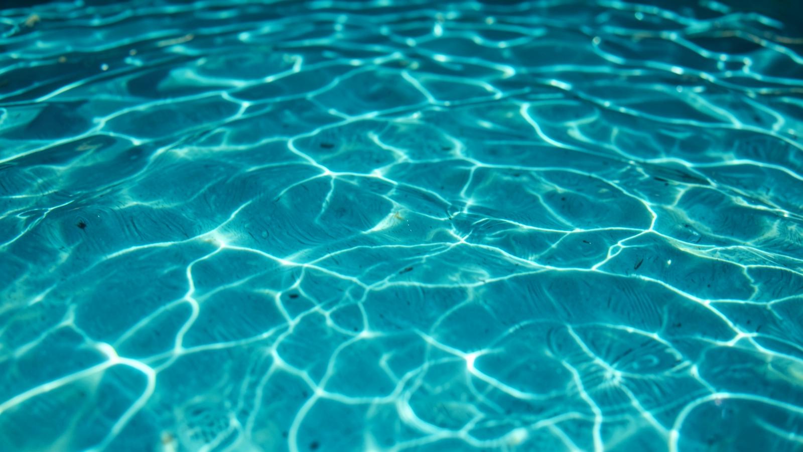 Crystal clear pool water with sunlight reflections